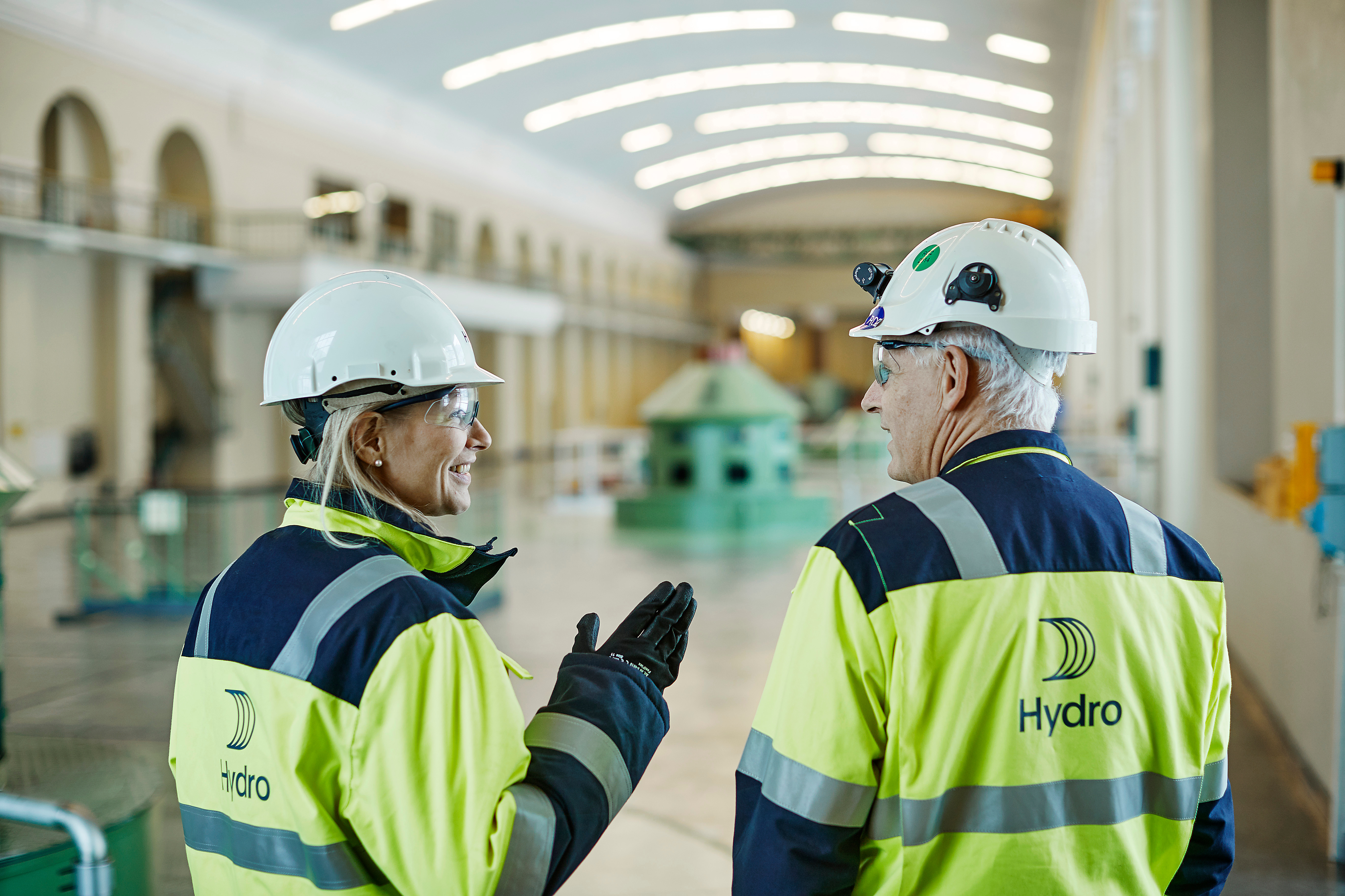 Hydro Mitarbeitende sprechen in einer Halle miteinander