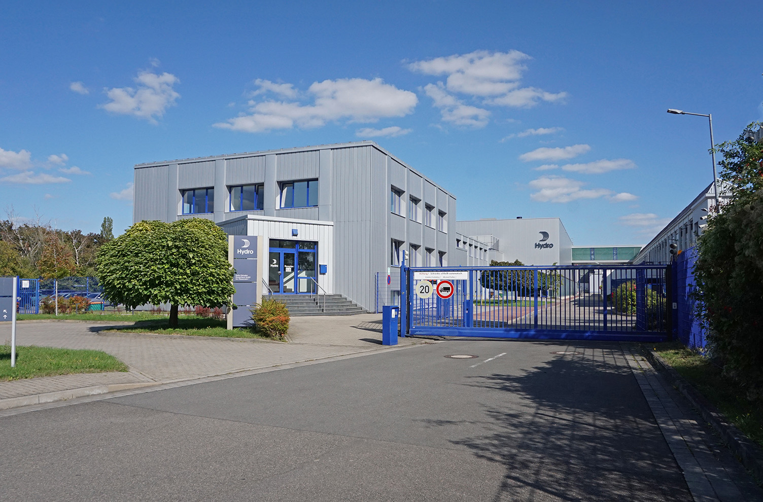 a blue gated building with trees and a blue sky