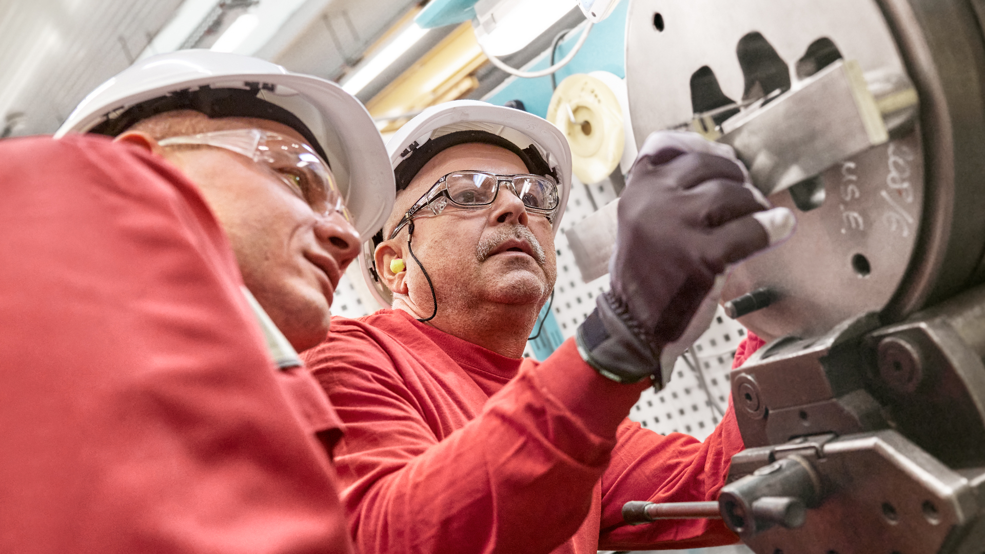 a few men in hardhats working on a machine